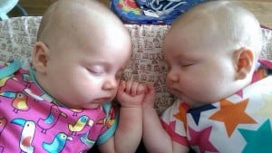 sleeping twins with hands touching