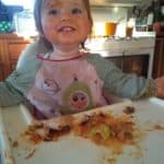 Toddler in high chair enjoying messy food