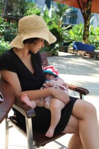 mother with a baby on her lap in the sun, both with sunhats