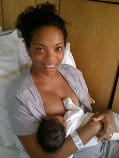 Smiling mother in hospital bed breastfeeding new baby