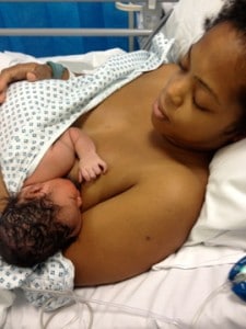 Breastfeeding mother and newborn baby in hospital bed